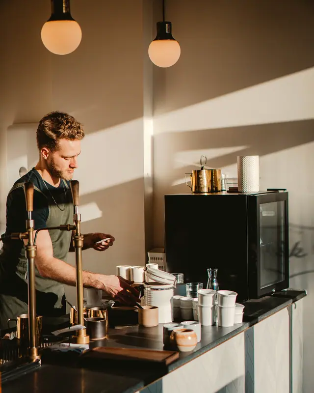A barista working behind a warm, wood-lined bar