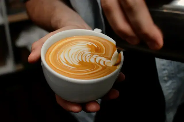 Hands holding a cup of latte art